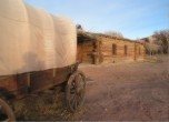 Bluff Fort -- Covered wagon with the Bluff Fort log meetinghouse in the background. Lamont Crabtree Photo